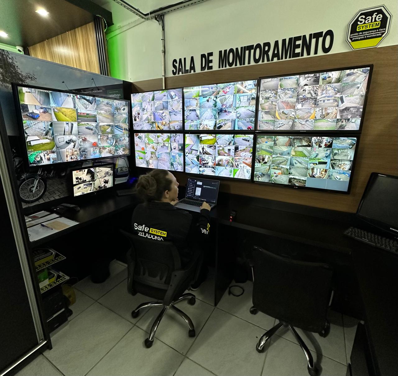 Sala de monitoramento da Safe System Zeladoria com parede de telas de câmeras